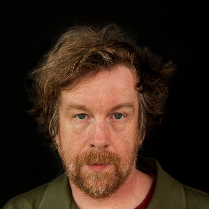 Writer Kevin Barry wears a green shirt against a black background