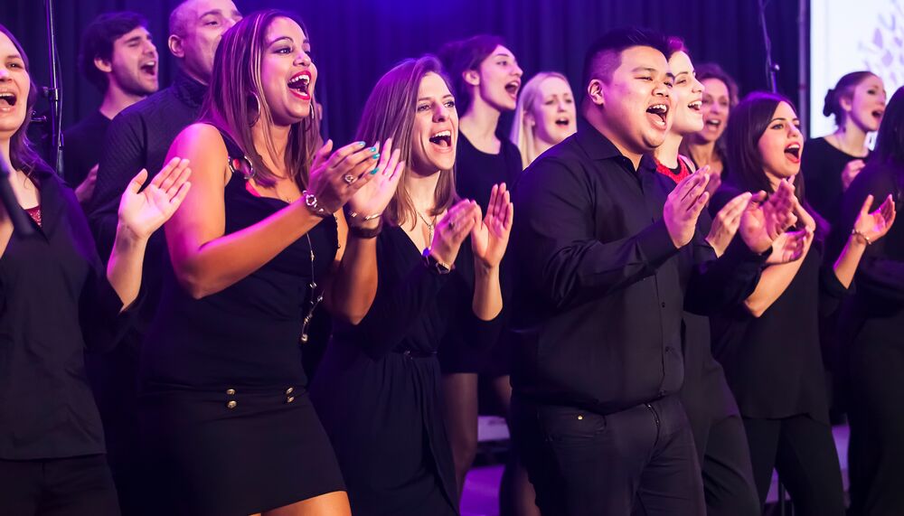 A mixed choir singing on stage, all wearing black