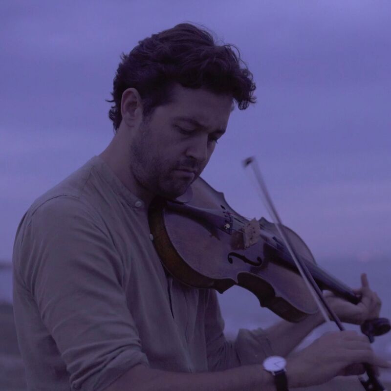 Lawrence Power playing the violin next to the ocean