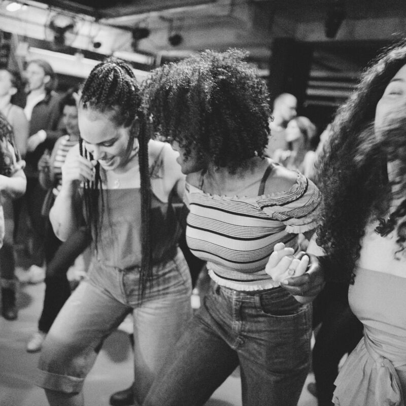 A group of women dancing in a line holding hands