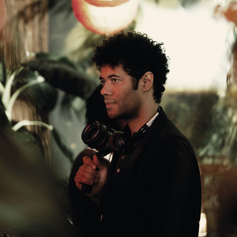 Richard Ayoade holding a camera in a jungle themed room