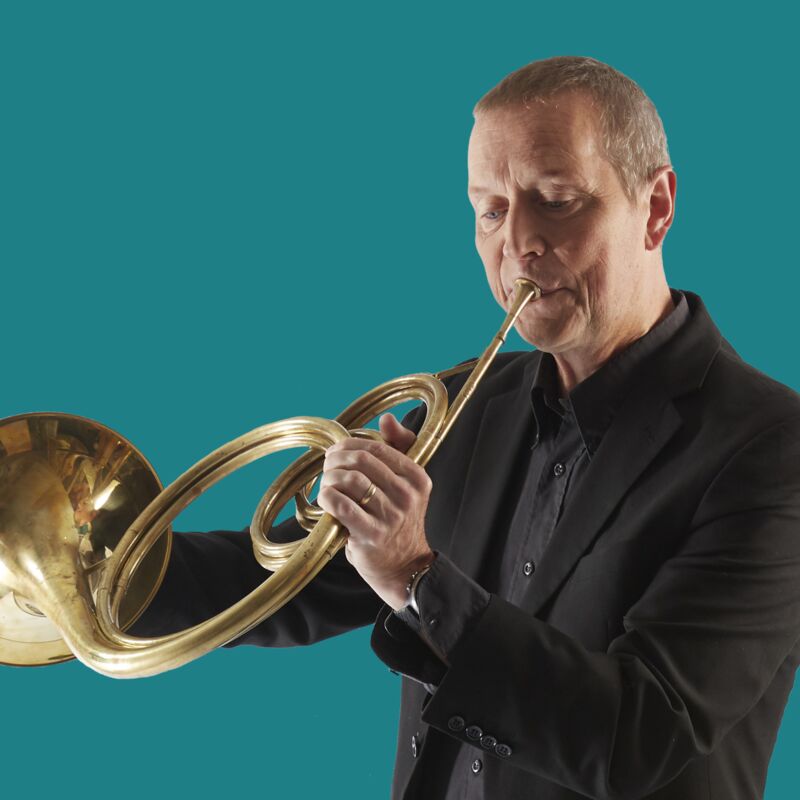 An 18th Century horn being played by Roger Montgomery, a white man dressed in black clothes