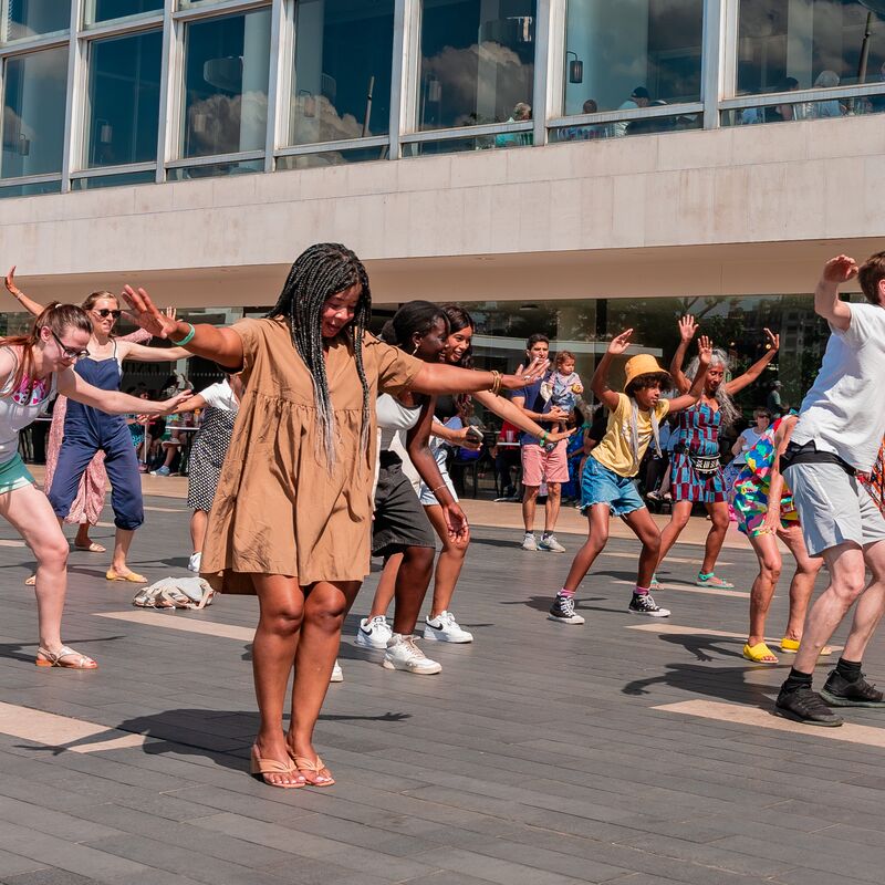 A crowd of people smiling and squatting with their hands in the air on the Riverside Terrace