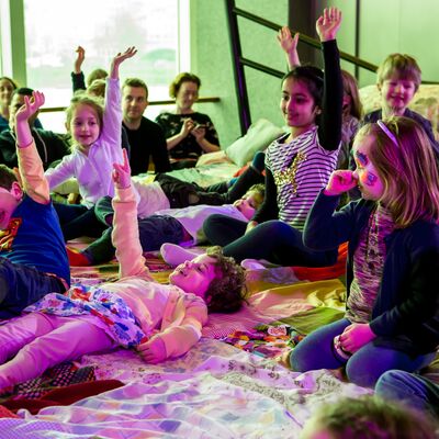 Children with their hands up on THE GIANT STORYTELLING BED at Imagine Children's Festival