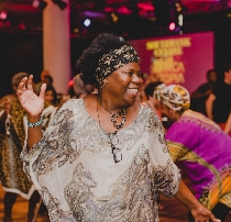 A smiling black woman dancing in The Clore Ballroom