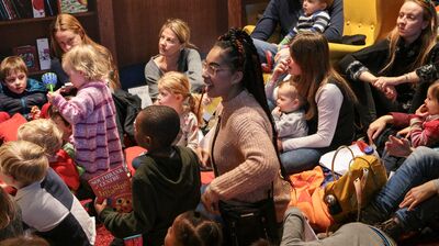 Toddlers with their parents sitting on the floor at Rug Rhymes event