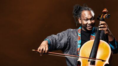 Abel Selaocoe playing Cello with one hand on the strings and the other holding the bow