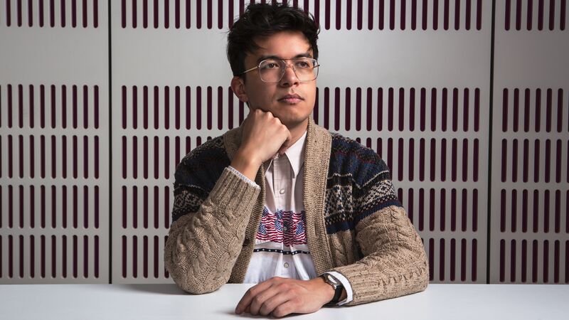 Comedian Phil Wang sits at a desk