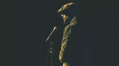 Anthony Anaxagorou stands at a microphone