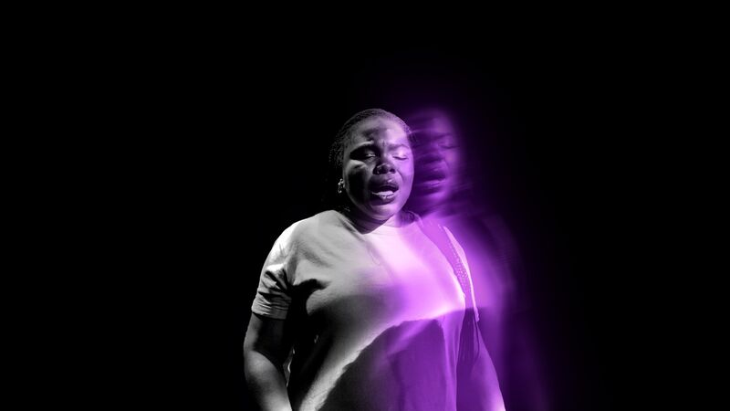 Victoria Oruwari singing, in a mostly black and white image with a purple echo of her.