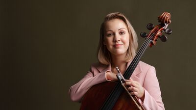 Cellist Senja Rummukainen holding her cello dressed in pink