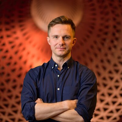 James McVinnie standing in front of an orange textured background