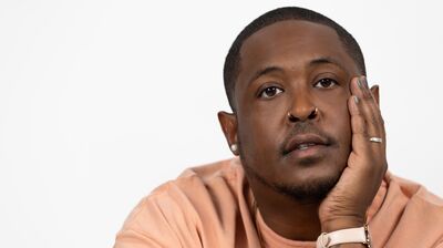 Danez Smith wearing an orange shirt against a white background.