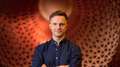 James McVinnie standing in front of an orange textured background