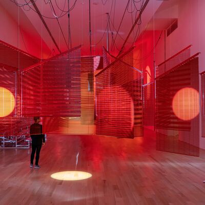 An installation with red venetian blinds and spotlights in a room.