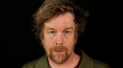 Writer Kevin Barry wears a green shirt against a black background