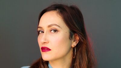 A woman with shoulder length brown/red hair in a light blue blouse