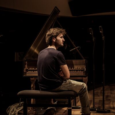 Jean Rondeau seated at a harpsichord with a back to the camera looking to the side