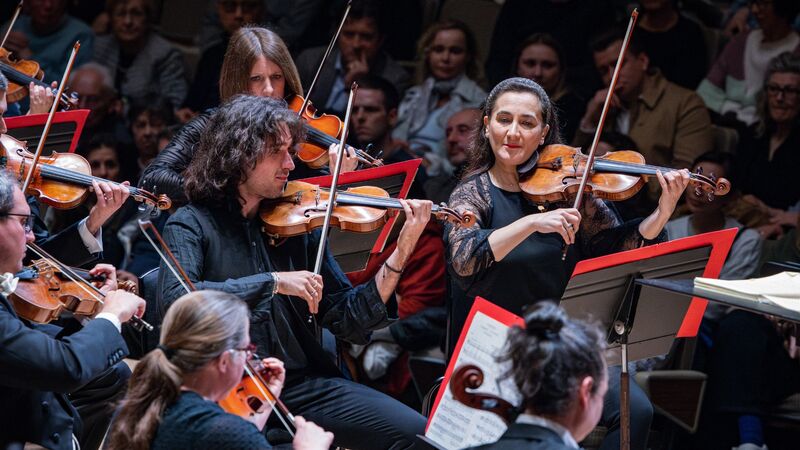 Two violinists playing within an orchestra