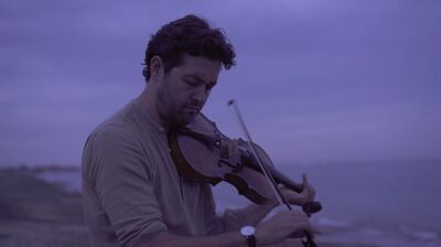 Lawrence Power playing the violin next to the ocean