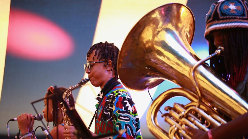 Three young jazz musicians playing the tuba, saxophone and singing perform on stage as part of Tomorrow's Warriors ensemble