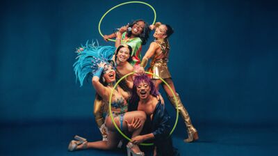 Five performers of Cocoa Butter Club pose with hoops and microphones 