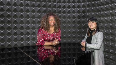 Song Yi Jeon and Dianne Reeves next to a piano, smiling at the camera