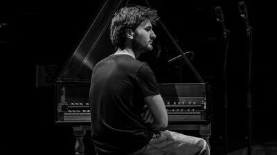 Jean Rondeau seated at a harpsichord with a back to the camera looking to the side