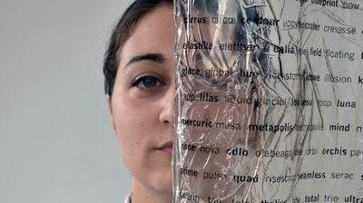 Artist's face behind a transparent page with black letters