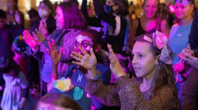 An audience dancing, with two children at the front clapping their hands