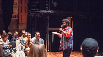 Person holding a mic standing in front of a group of people