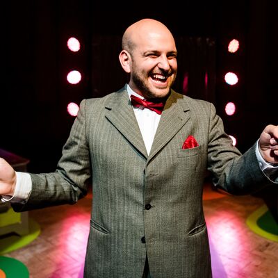 A man wearing a formal grey pinstripe jacket and a red bowtie