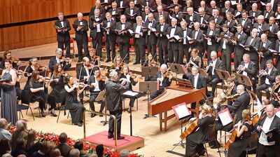 A large orchestra and choir in suits and dresses performing at Christmas time