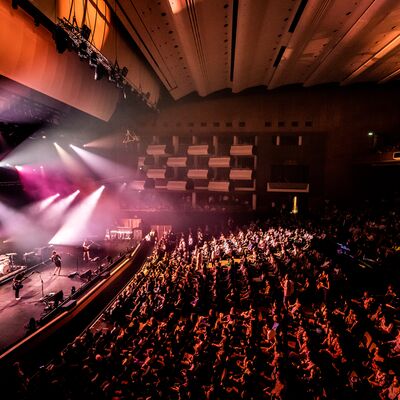 A band on stage performing in front of a full crowd in the Royal Festival Hall