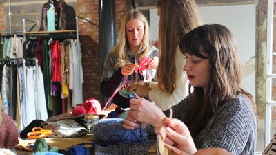 A group of women sat around a wooden table doing arts and crafts