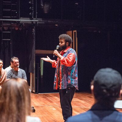 Person holding a mic standing in front of a group of people