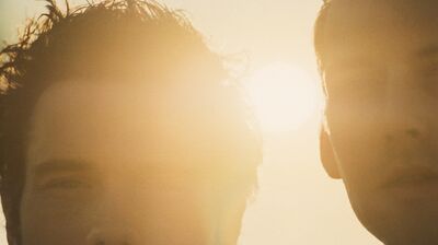 close-up of two individuals in a sun-drenched scene, with soft lighting creating a warm and atmospheric effect