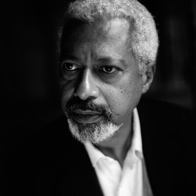 Black and white image of author Abdulrazak Gurnah wearing a shirt and jacket.