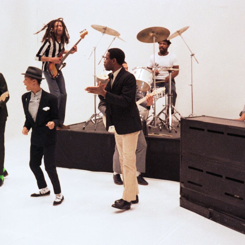 Still from music video for The Selecter, shows the band performing against a white backdrop