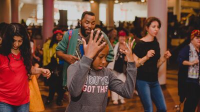 A group of people dancing with a young child at the front