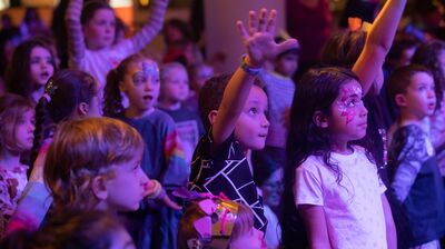 Group of children, some with their faces painted and some with arms raised