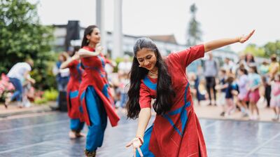 2 woman dancing outside in red and blue traditional Indian dress.