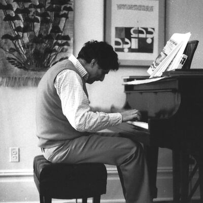 Edward Said sits at a grand piano looking down at the keyboard