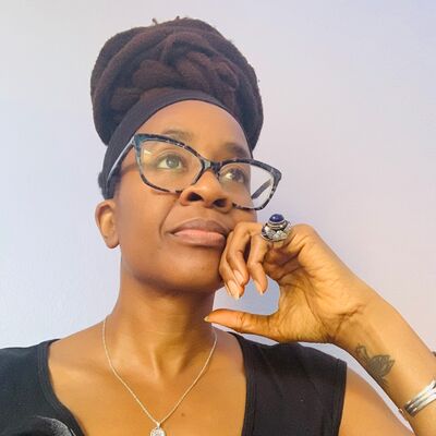 Author Nnedi Okorafor wearing a black T shirt resting her head on her hand.