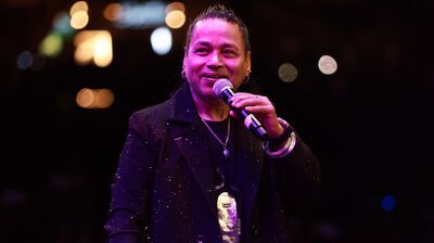Kailash Kher smiling holding a microphone wearing a sparkly suit