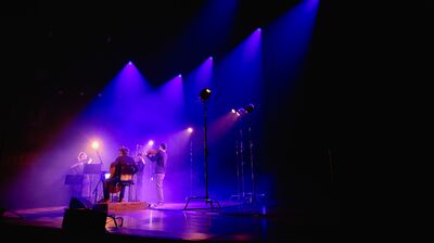 A group of musicians on stage, lit by blue lighting