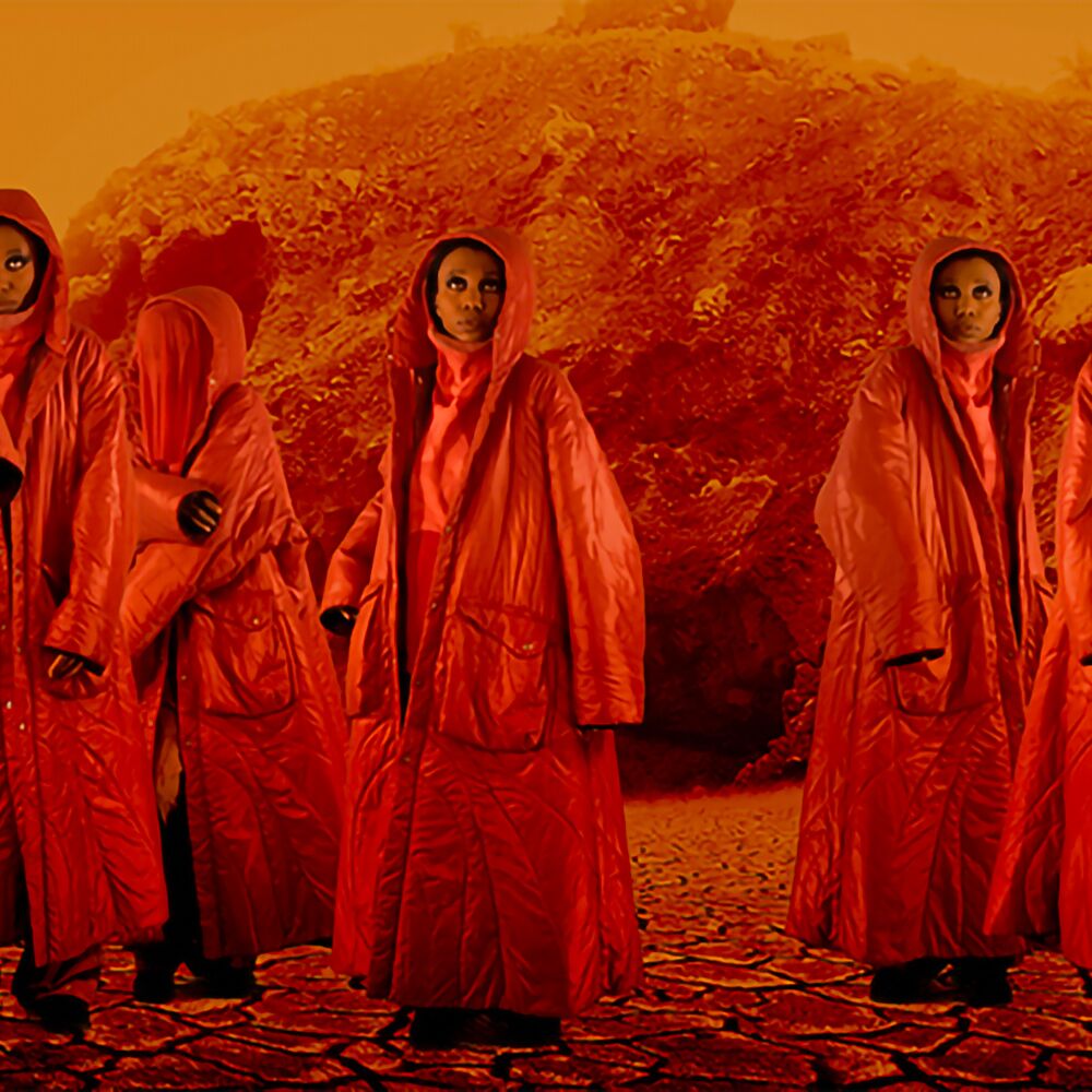 Multiple images of same person in red jacket and hood looking up on a background that looks like the surface of the sun