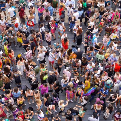 A Birdseye view of people having fun with pride flags on their clothes outside on the roof terrace.