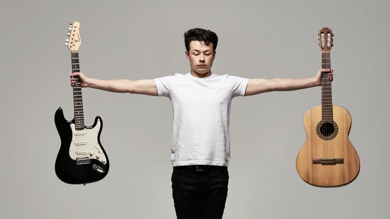Sean Shibe holding his guitars