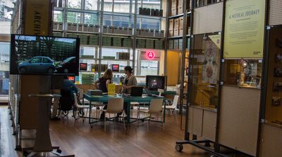 The Archive Studio including a tv screen and a few people sitting at chairs amongst storage boxes